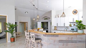 A modern kitchen with a central island, white cabinets, and pendant lighting.