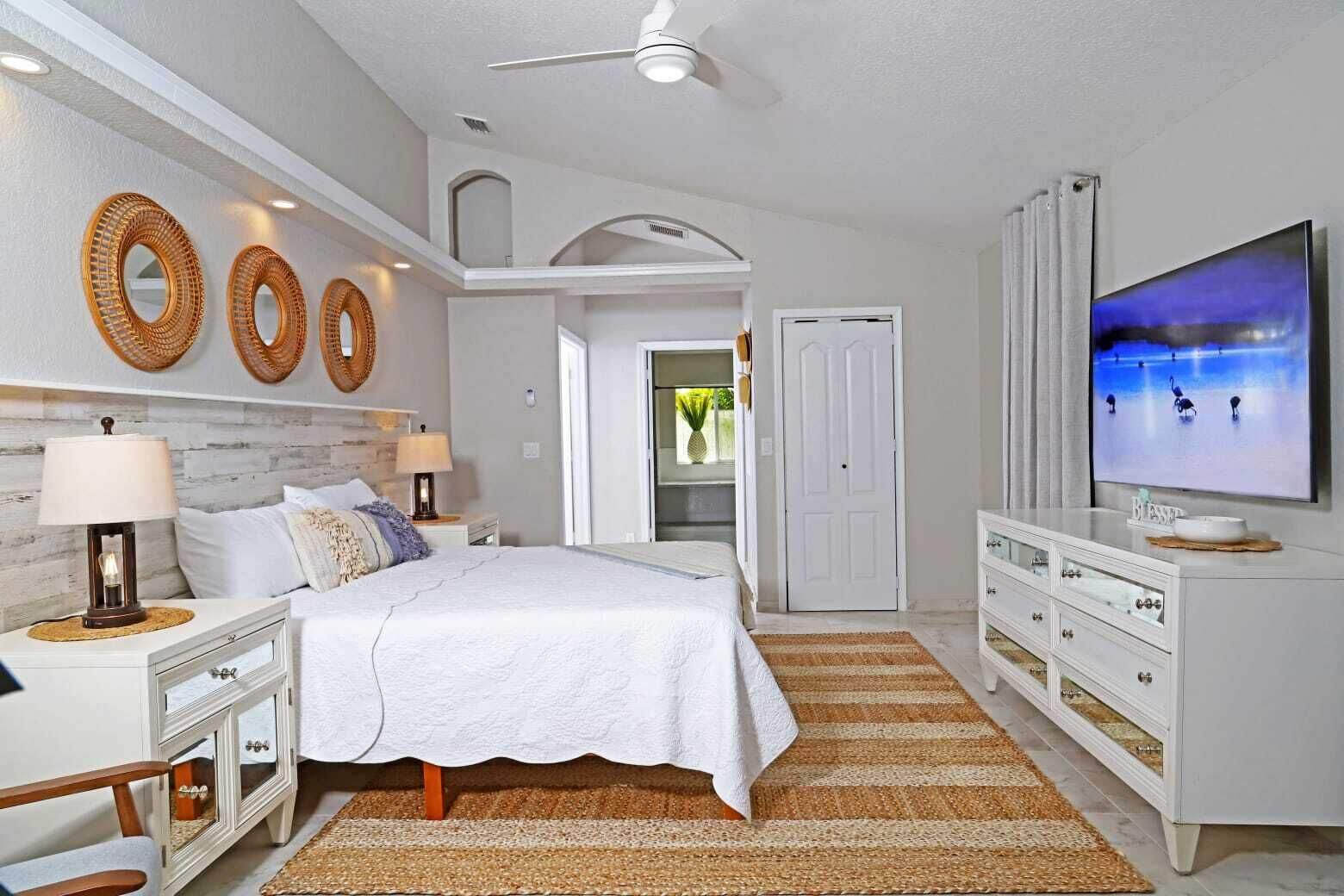 A bedroom with a bed, nightstands, a dresser, a television, and decorative wall art.