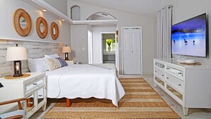 A bedroom with a bed, nightstands, a dresser, a television, and decorative wall art.