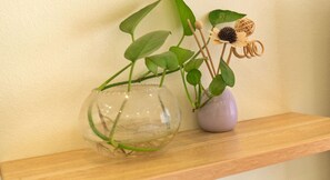Une étagère en bois sur laquelle reposent deux vases en verre contenant des plantes.