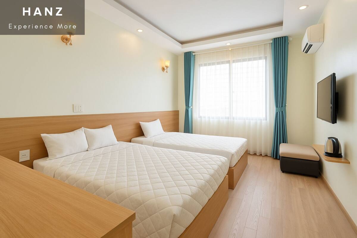 A hotel room with two beds, a TV, a coffee machine, and a window with curtains.