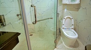 Une salle de bain équipée de toilettes, d’une douche à parois de verre et d’une barre d’appui.
