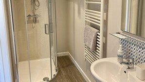 A bathroom with a glass shower enclosure, a white sink, and a towel rack. - Romantic hideaway cottage, near Bridport, Dorset (Bridport)