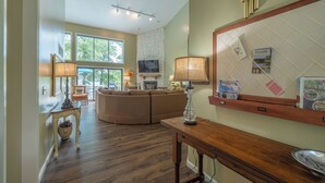 A living room with a fireplace, a television, a large mirror, and a dining area with a table and chairs. - The Aspen Cottage by Innsbrook Vacations! (Innsbrook)