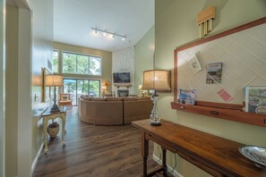 A living room with a fireplace, a television, a large mirror, and a dining area with a table and chairs. - The Aspen Cottage by Innsbrook Vacations! (Innsbrook)