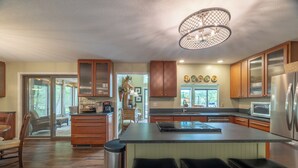 A spacious kitchen with a large island, wooden cabinets, and a modern chandelier. - The Aspen Cottage by Innsbrook Vacations! (Innsbrook)