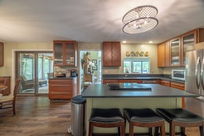 A spacious kitchen with a large island, wooden cabinets, and a modern chandelier. - The Aspen Cottage by Innsbrook Vacations! (Innsbrook)