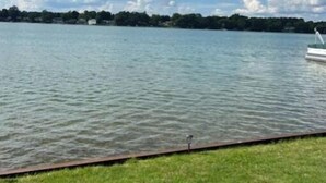 Un lago tranquillo con una sponda erbosa e una piccola barca.