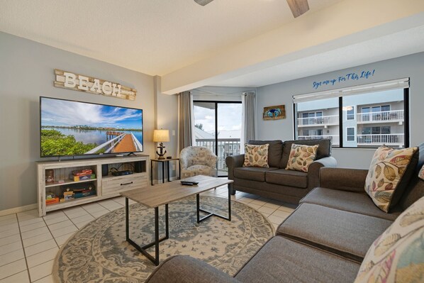 A living room with a TV, sofa, and a 'BEACH' sign.