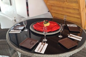 A round dining table with a red cloth centerpiece, surrounded by four square placemats, wine glasses, and cutlery. - 2brCabin-Fireplace-HotTub-Sauna-SkiResort (Brasov Bran Predelut)