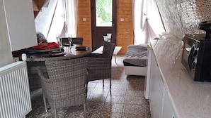 A compact kitchen with a dining area, a small sofa, and a washing machine.