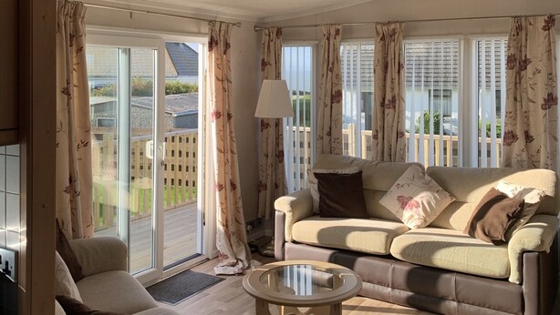 A spacious living room with a sofa, armchairs, and a glass coffee table. - Immaculate 2-Bed Lodge in Monreith (Newton Stewart)