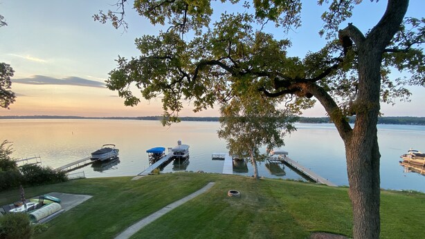 Une terrasse avec coin salon extérieur, un quai avec des bateaux et une vue sur le lac.