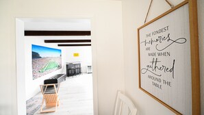 Een kamer met een lijst met een citaat aan de muur, zicht op een sportveld door een deur, en een stoel op de voorgrond.
