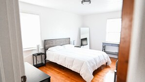 Een slaapkamer met een bed, een bureau, een stoel, een televisie en een dressoir.