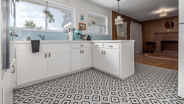 A modern kitchen with white cabinets, a large window, and a patterned floor. - Casa Cremosa (Hot Springs)