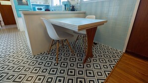A kitchen with a white table, two white chairs, a blue oven, and a patterned floor. - Casa Cremosa (Hot Springs)