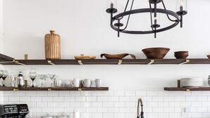 Une cuisine moderne avec des meubles de couleur sombre, un plan de travail blanc, un panneau indiquant le coin café et un lustre.