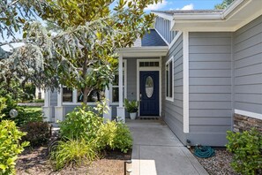 A residential house with a front porch, a blue door, and a garden with various plants. - Outstanding newly remodeled and updated home in upscale, desirable neighborhood! (Garden City)