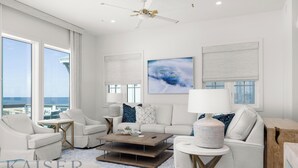 Ein modernes Wohnzimmer mit Meerblick, ausgestattet mit einer Couch, Sesseln, einem Couchtisch und Kunstwerken an den Wänden.