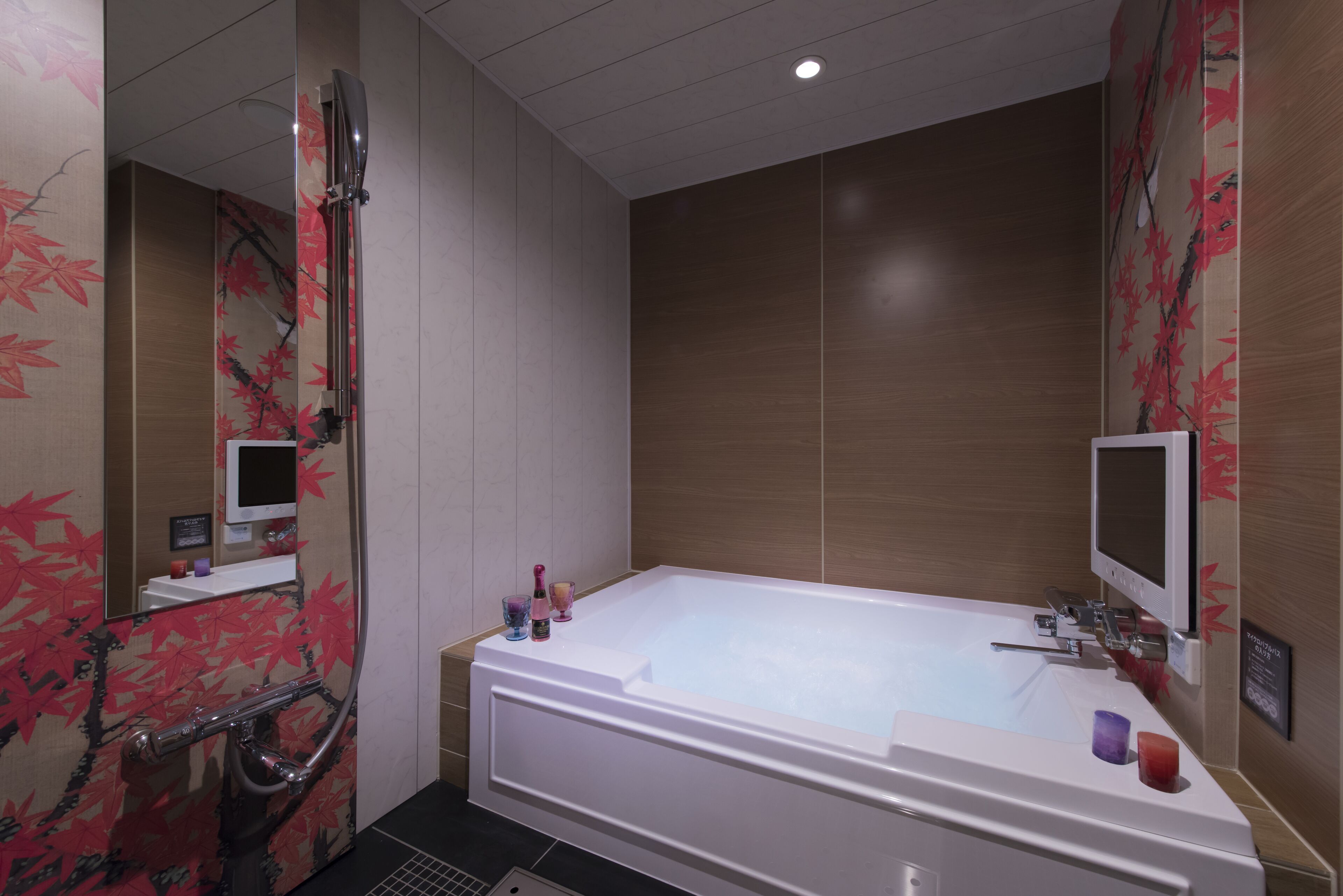 Un baño moderno con una bañera grande, un cabezal de ducha manual y un televisor montado en la pared.