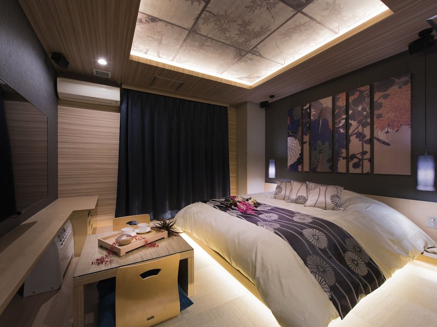 A modern hotel room with a bed, bedside table, and a large artwork on the wall.
