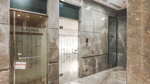 Entrada de un spa con puerta de vidrio, señalizada con las palabras SAUNA y VAPOR.