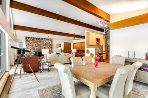 Un coin repas avec une table en bois, des chaises rembourrées et un mur en pierre en arrière-plan.