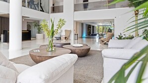 A spacious lobby with a reception desk, seating areas, and indoor plants.