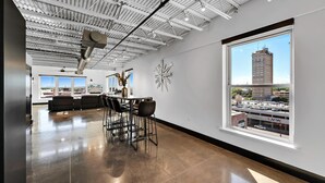 Ein großzügiges, modernes Interieur mit hoher Decke, einem Essbereich mit Stadtblick und einem großen Fenster.