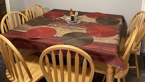 Comedor con mesa de madera, individuales rojos y un reloj de pared.