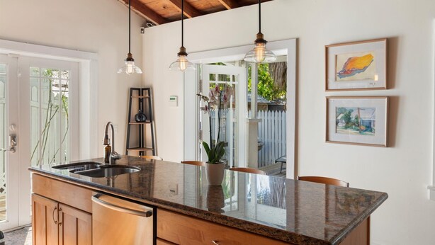 A kitchen with a granite countertop, stainless steel sink, wooden cabinets, and pendant lighting. - Old Town Key West Cottage (Naval Air Station Key West)