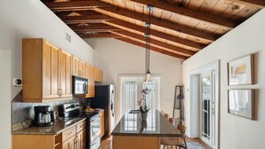 A kitchen with wooden cabinets, a central island, and a hanging light fixture. - Old Town Key West Cottage (Naval Air Station Key West)