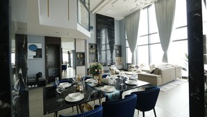 A modern dining area with a glass table set for six, surrounded by blue upholstered chairs. - The Penthouse Residence (Phnom Penh)