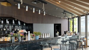 A modern bar area with a marble countertop, bar stools, and a variety of bottles and glasses. - The Penthouse Residence (Phnom Penh)