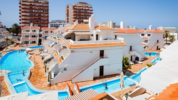 A resort with multiple swimming pools, a central staircase, and a view of surrounding buildings. - Las Floritas 23 Terrace and Swimming Pool (Playa de las Américas)