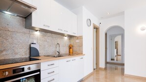 A modern kitchen with white cabinets, a stainless steel range hood, a built-in oven, and a granite countertop. - Las Floritas 23 Terrace and Swimming Pool (Playa de las Américas)