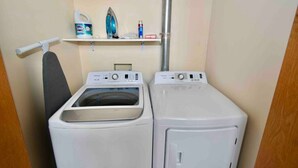 A laundry area with two front-loading washing machines, a drying rack, and a shelf with laundry supplies. - ★ THE PAD ★ KING BED ★ (Kansas City)