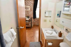 A bathroom with a wooden door, a sink, a mirror, and a towel rack. - ★ THE PAD ★ KING BED ★ (Kansas City)