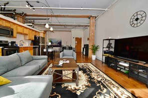A modern living space with a sofa, coffee table, TV, kitchen area, and dining area. - ★ THE PAD ★ KING BED ★ (Kansas City)