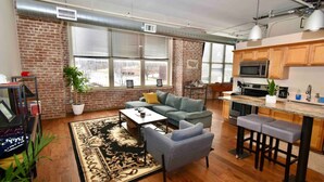 A spacious living area with a sofa, coffee table, and a kitchen with a bar area. - ★ THE PAD ★ KING BED ★ (Kansas City)