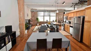 A modern kitchen with a dining area, featuring a large table, wooden cabinets, and a stainless steel refrigerator. - ★ THE PAD ★ KING BED ★ (Kansas City)