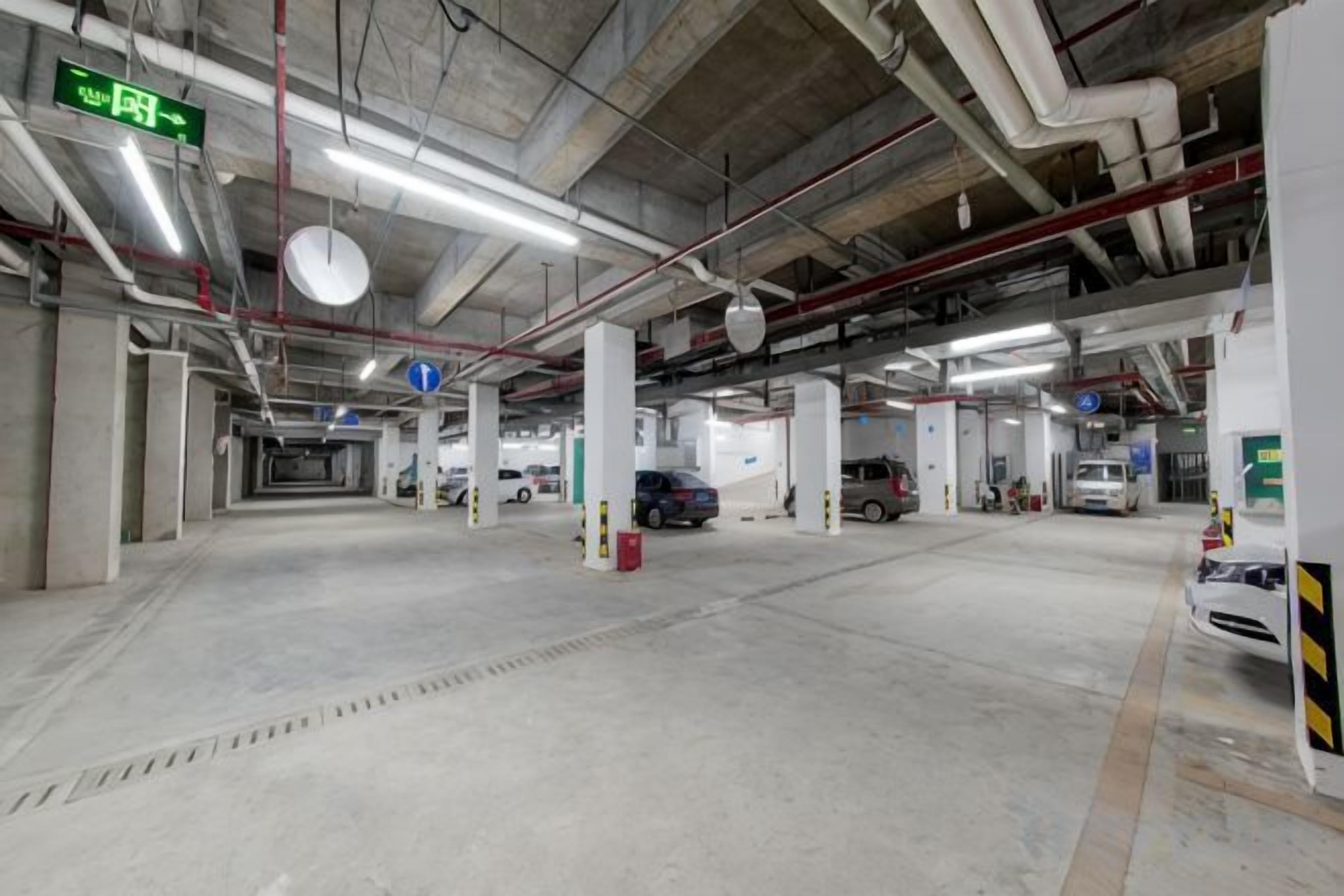 A multi-level parking garage with concrete pillars, overhead lighting, and directional signs.