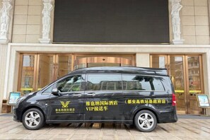Un fourgon noir était garé devant un immeuble doté de grandes portes vitrées et d’une enseigne.