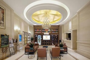 A hotel lobby with a chandelier, seating area, reception desk, and a large bookshelf. - Vienna International Hotel (Du'an Station) (Du'an)