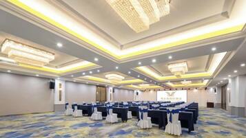 A conference room with rows of tables, chairs, and a stage.