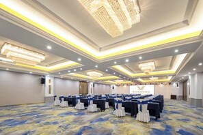 A conference room with rows of tables, chairs, and a stage. - Vienna International Hotel (Du'an Station) (Du'an)