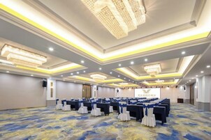 A conference room with rows of tables, chairs, and a stage.