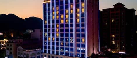 A multi-story hotel with illuminated windows and a prominent sign at the top.