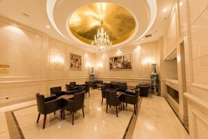 A hotel lobby with a chandelier, seating area, and artwork on the walls. - Vienna International Hotel (Du'an Station) (Du'an)
